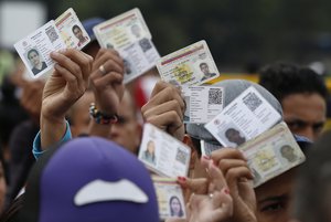 In this Feb. 22, 2018 photo, Venezuelan citizens hold up their identification cards for inspection by the Colombian immigration police, in Cucuta, Colombia, on the border with Venezuela.