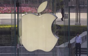 A man stands near the logo of Apple in Shanghai, China, Tuesday, April 2, 2013. Apple apologized to Chinese consumers after government media attacked its repair policies for two weeks in a campaign that reeked of economic nationalism. (AP Photo/Eugene Hoshiko)