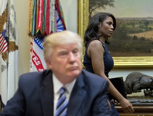 White House Director of communications for the Office of Public Liaison Omarosa Manigault, right, walks past President Donald Trump during a meeting on healthcare in the Roosevelt Room of the White House in Washington, Monday, March 13, 2017.