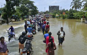 People move past a flooded road in Thrissur, in the southern Indian state of Kerala, Friday, Aug. 17, 2018.