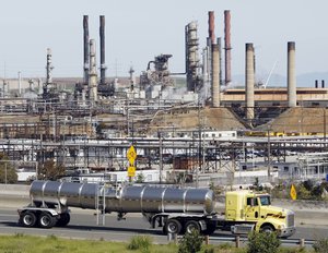 In this March 9, 2010 file photo, a tanker truck passes an oil refinery in Richmond, Calif. The Environmental Protection Agency (EPA) announced new rules Tuesday to reduce toxic air pollution from oil refineries by forcing operators to adopt new technology that better monitors and controls emissions.