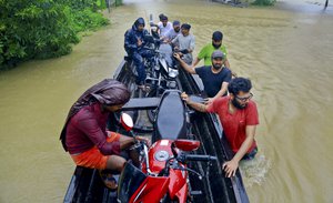 People salvage motorcycles in a country boat in a flooded area at Kainakary in Alappuzha district, Kerala state, India, Friday, Aug. 17, 2018.