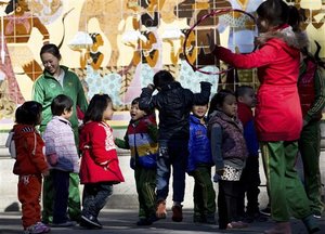 Kindergarten teachers play with children during an outdoor activity at the Ritan Park in Beijing Wednesday, Oct. 31, 2012. A government think tank says China should start phasing out its one-child policy immediately and allow two children for every family by 2015. It remains unclear whether Chinese leaders are ready to take that step.