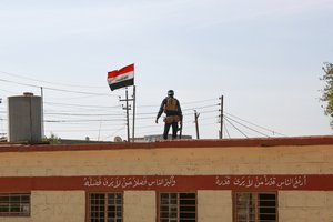 File - An Iraqi federal police officer provides security for students at a primary school in Aski Mosul, Iraq, Nov. 13, 2017.