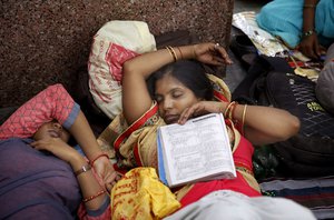 Candidates appearing for Uttar Pradesh state high school teachers examinations sleep on a platform after arriving at a railway station past midnight in Allahabad, India, Sunday, July 29, 2018.