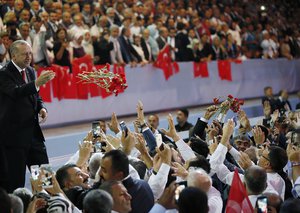 Turkey's President Recep Tayyip Erdogan, accompanied by his wife Emine, left, throws flowers to his supporters as he arrives to deliver a speech at his ruling Justice and Development Party (AKP) congress in Ankara, Turkey, Saturday, Aug. 18, 2018.