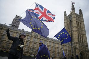 File - Demonstrators opposing Brexit wave flags as The European Commission's Chief Negotiator for the UK exiting the European Union, Michel Barnier is at 10 Downing Street for a meeting, outside the Houses of Parliament, London, Monday, Feb. 5, 2018.