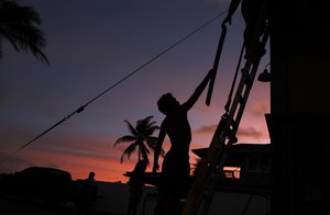 Kainalu Kitashima hands his father a piece of wood to help tie down their tiny home in preparation for Hurricane Lane, Wednesday, Aug. 22, 2018, along Ewa Beach in Honolulu.