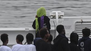 Migrants stand on the deck of the Italian Coast Guard ship Diciotti, moored at the Catania harbor, Tuesday, Aug. 21, 2018.