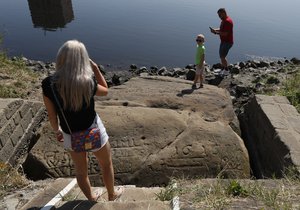 People visit one of the so called "hunger stones" exposed by the low level of water in the Elbe river in Decin, Czech Republic, Thursday, Aug. 23, 2018