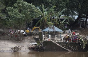 An excavator removes muck caused due to recent floods on the banks of Periyar river, on the outskirts of Kochi in the southern state of Kerala, India, Wednesday, Aug. 22, 2018.