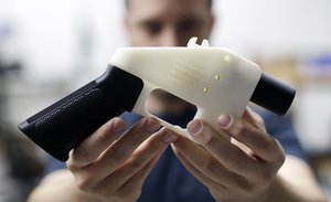 In this Aug. 1, 2018, file photo, Cody Wilson, with Defense Distributed, holds a 3D-printed gun called the Liberator at his shop in Austin, Texas.