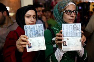 Two Syrian women who live in Iran show their passports while waiting to vote in their country's presidential election at the Syrian Embassy in Tehran, Iran, Wednesday, May 28, 2014