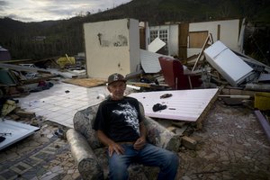 Luis Cosme poses sitting in an armchair in what is left of his house destroyed by Hurricane Maria, in Morovis, Puerto Rico, Sunday, Oct. 1, 2017.