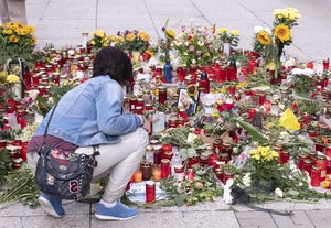 A woman mourns in front of candles and flowers at the scene of an altercation in Chemnitz, Germany, Friday, Aug. 31, 2018.