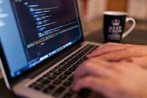 Man hands writing Computer programming coding on MacBook Pro computer - Technology