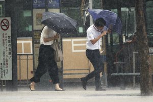 Pedestrians struggle to hold umbrellas as typhoon