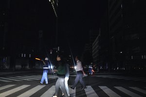 Police officers guide traffic as pedestrian walk in the blackout on the center of Sapporo city, Hokkaido, northern Japan, Thursday, Sept. 6, 2018. A powerful earthquake jolted Japan's northernmost main island of Hokkaido.