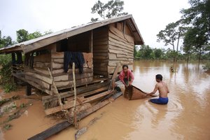 Kongvilay Inthavong and his wife Thongla clean up their house as the floodwaters start to recede i in Sanamxay district, Attapeu province, Laos on Thursday, July 26, 2018.