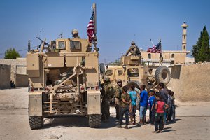 File - A group of children gather around a U.S. military convoy conducting a patrol in their village along the demarcation line outside Manbij, Syria, July 14, 2018.