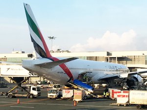 Emirates Airways airplane in the middle of vehicles, cargos, and equipments at an airport. Taken on October 2017.