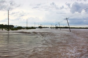 File - A road is obscured during severe flooding in Rosenberg, Texas, June 2, 2016.