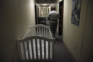 In this June 26, 2014 file photo, a federal employee walks past cribs inside of the barracks for law enforcement trainees turned into immigrant detention center at the Federal Law Enforcement Center (FLETC) in Artesia, N.M.