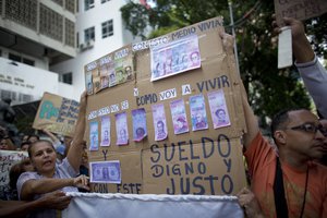 Nurses holds a sign with a fake Venezuelan's bills, representing how low their salaries have been devalued by inflation, during a protests against the government of President Nicolas Maduro, in Caracas, Venezuela, Thursday, Aug. 16, 2018.