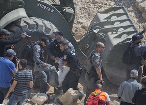 Israeli border police arrest protesters and activists blocking Israeli army bulldozer operating at the West Bank Bedouin community of Khan al-Ahmar, Friday, Sept. 14, 2018.