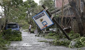 A resident walks beside a toppled basketball court after Typhoon Mangkhut barreled across Tuguegarao city, Cagayan province, northeastern Philippines, Saturday, Sept. 15, 2018.