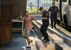 FILE. In this Tuesday, July 31, 2018 file photo, Pyotr Verzilov, a member of the feminist protest group Pussy Riot, gestures as he escorted to the courtroom in Moscow, Russia. Russian news reports say Verzilov, a member of Russian punk protest group Pussy Riot, has been hospitalized in grave condition for what could be a possible poisoning.