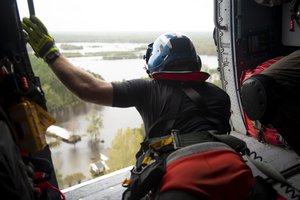 A member of the Coast Guard looks out from a helicopter over the severe flooding in North Carolina caused by Tropical Storm Florence, Sept. 16, 2018.