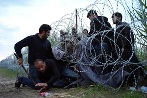 FILE - In this Aug. 26, 2015, file photo, Syrian refugees cross into Hungary underneath the border fence on the Hungarian - Serbian border near Roszke, Hungary. From the three-year-old boy who washed ashore on a Turkish beach to the 71 migrants who suffocated in a truck in Austria to the daily scenes of chaos unfolding in European cities as governments try to halt a human tide heading north. There is no let up to the horrors that Syria’s civil war keeps producing. Syria’s brutal conflict, now in its fifth year, has touched off the greatest humanitarian crisis of our time. About 250,000 people have been killed and more than one million wounded since March 2011, according to U.N. officials. (AP Photo/Bela Szandelszky, File)