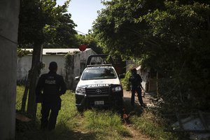 Police stand guard near the site where dozens of mass graves were found holding at least 170 human skulls in Arbolillo, Veracruz state, Mexico, Monday, Sept. 17, 2018.