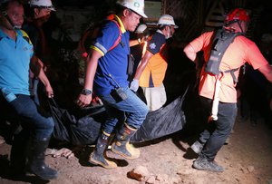 Rescuers carry a body of a victim after being dug up from the rubble following a landslide that buried dozens of homes in Naga city,  Cebu province central Philippines on Thursday Sept. 20, 2018.