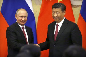 Russian President Vladimir Putin, left, and Chinese President Xi Jinping shake hands at the end of a joint press briefing at the Great Hall of the People in Beijing, Friday, June 8, 2018.