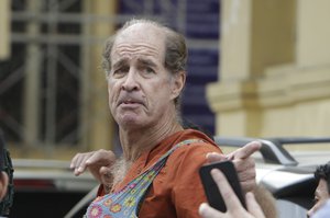 In this Jan. 17, 2018, photo, Australian filmmaker James Ricketson, 68, gestures as he is escorted by prison guards at the Cambodian Supreme Court in Phnom Penh, Cambodia.