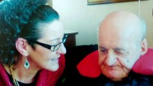 Noleen Hausler with her father Clarence Hausler sit together. He wears a cushion to prop his head up.