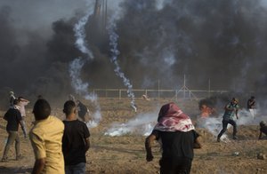 Palestinian protesters run for cover from teargas fired by Israeli troops during a protest at the Gaza Strip's border with Israel, 28 September, 2018.