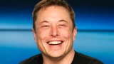 Tesla CEO Elon Musk smiles at a press conference.