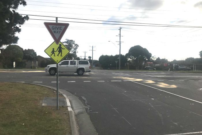 A white car passes through an intersection.