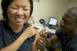 Chief Logistics Specialist Tam Colbert, assigned to the supply department of the amphibious assault ship USS Bon Homme Richard, reacts to a flu shot administered by Chief Hospital Corpsman Yahahn Thompson.