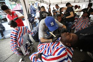 Venezuelan migrants get free haircuts and shaves, in Bogota, Colombia, Thursday, Sept. 27, 2018.