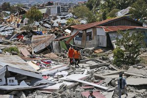 Rescuers carry a body bag containing the remains of an earthquake victim through a neighborhood flattened by Friday's earthquake in Palu, Central Sulawesi, Indonesia Indonesia, Tuesday, Oct. 2, 2018.