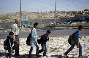 File - In this photo taken Monday, April 21, 2014, Ahmed Khatib walks with four of his six children along the separation barrier between the West Bank village of Hizme and the city of Jerusalem.