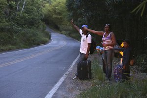 In this March 9, 2018 photo, Venezuelans Jose Guillen and his wife July Bascelta hitch hike with their 9-year-old twins Angel David and Ashley Angelina along highway BR 147 after crossing the border into Brazil near Pacaraima, Roraima state, Brazil.