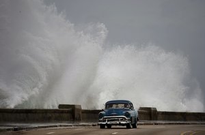 Waves crash against the Malecon, triggered by the outer bands of Hurricane Michael, as man drives past in a private, classic American car in Havana, Cuba, Tuesday, Oct. 9, 2018.