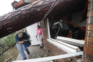 Megan Williams, left, and roommate Kaylee O'Brian take belongings from their destroyed home after several trees fell on the house during Hurricane Michael in Panama City, Fla., Wednesday, Oct. 10, 2018.