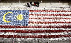 Students watch a giant Malaysian national flag made of coconut shells at Selayang in Kuala Lumpur, Malaysia, Monday, Aug. 28, 2017.