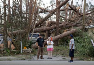 Joyce Fox, center stands in front of her heavily damaged home in the aftermath of Hurricane Michael in Panama City, Fla., Thursday, Oct. 11, 2018.